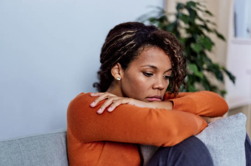 Woman looking serious with head on arms showing the physical and mental impact of trauma and eating disorders